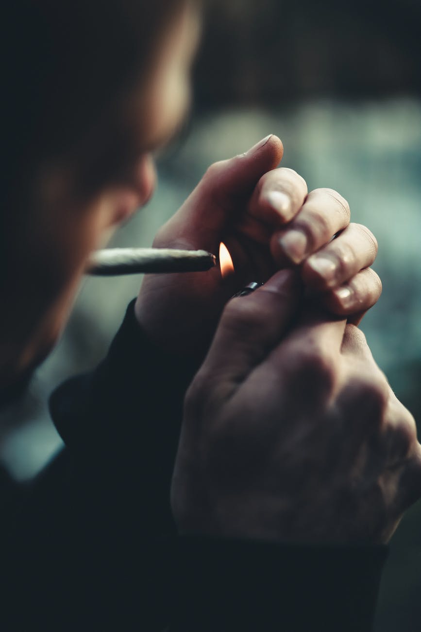 selective focus photography of man lighting cigarette