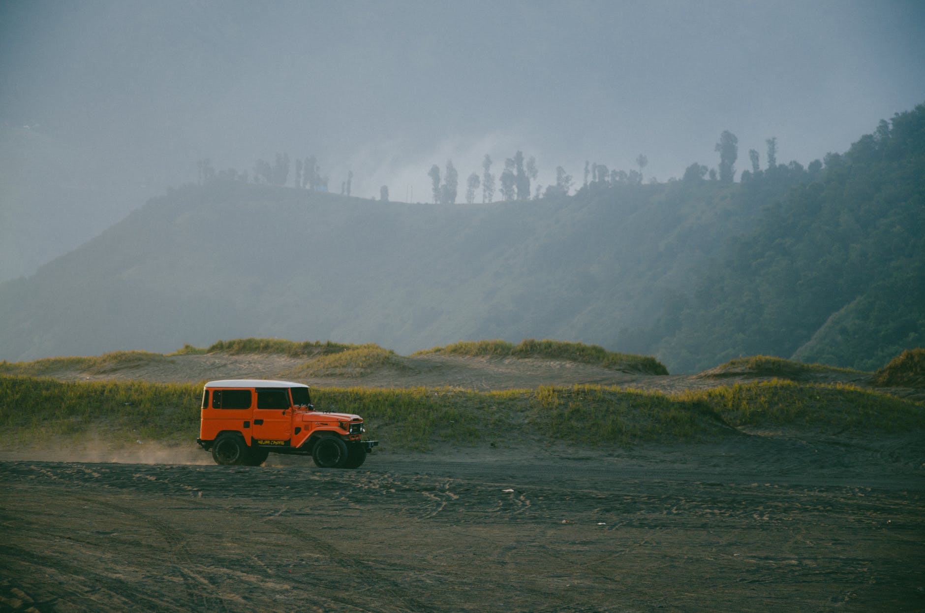 orange vehicle driving on dirt road